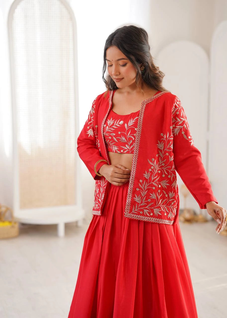 Woman wearing a red traditional outfit with floral embroidery in a bright room.
